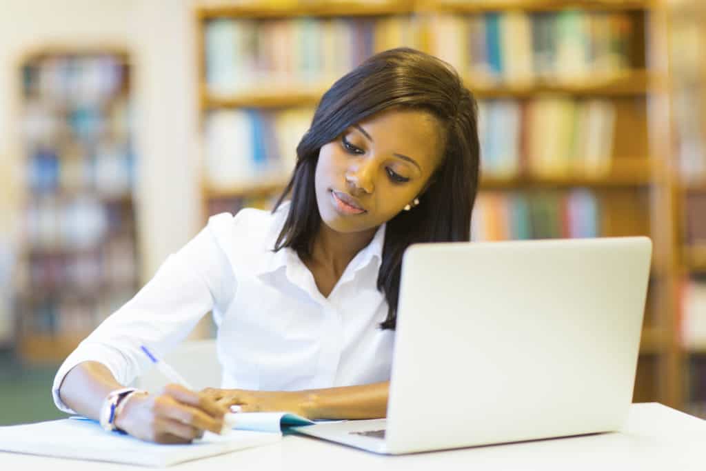 Young woman takes notes in front of a computer