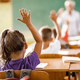 Girl in a classroom raising her hand