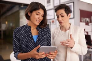 Professional women looking at iPad, talking