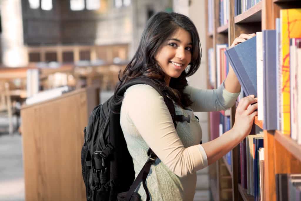 A shot of an asian student getting books in a library