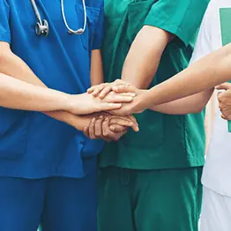 Medical professionals with their hands in a huddle formation