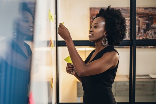 Woman pasting sticky notes on board