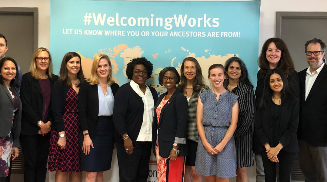 Group photo of women in front of #WelcomingWorks banner