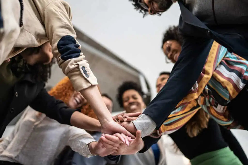 Group of people putting hands in the middle of a team huddle