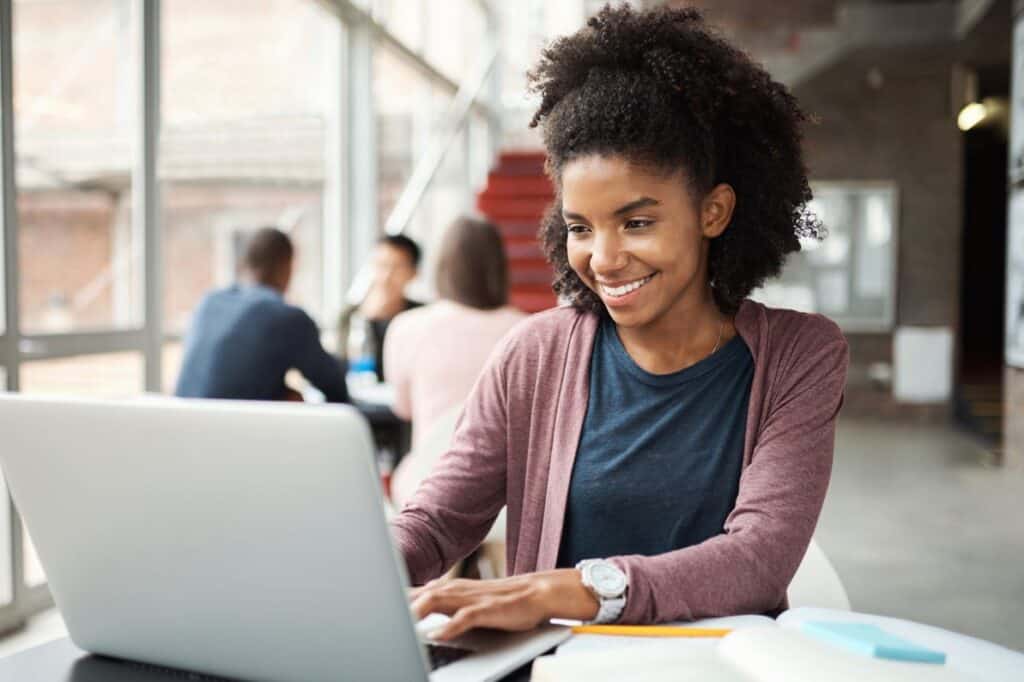 A smiling woman works at a laptop.