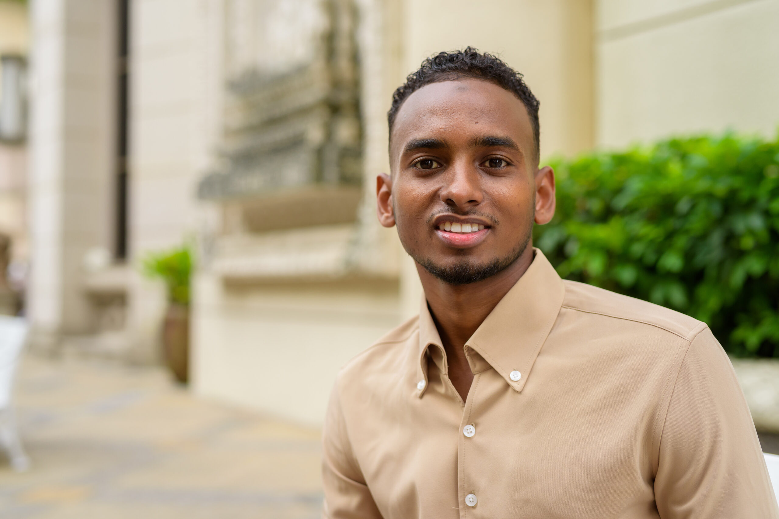 Portrait of handsome black young African businessman wearing casual clothes outdoors in city