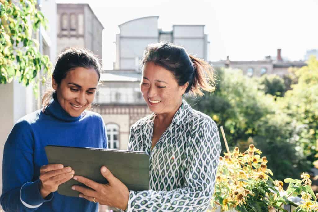 Two women smiling at tablet (Working Nav blog image)